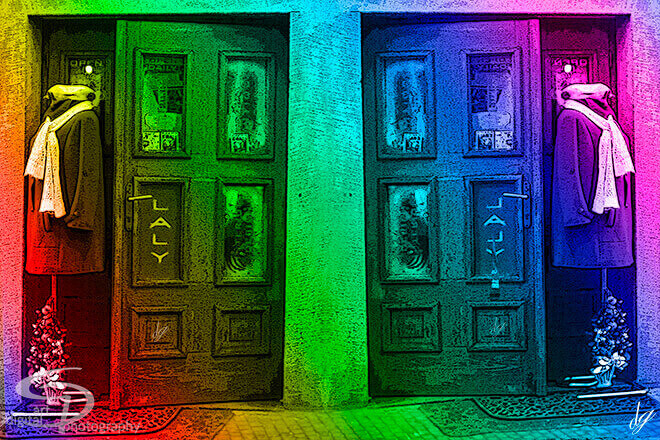 Two old wooden doors illuminated in vivid rainbow colors.
